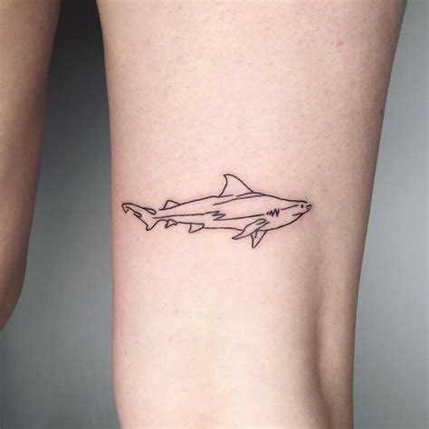 a small tattoo of a shark on the side of a woman's leg,