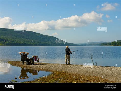 Two anglers fishing from the beach, Coniston, Lake District National ...