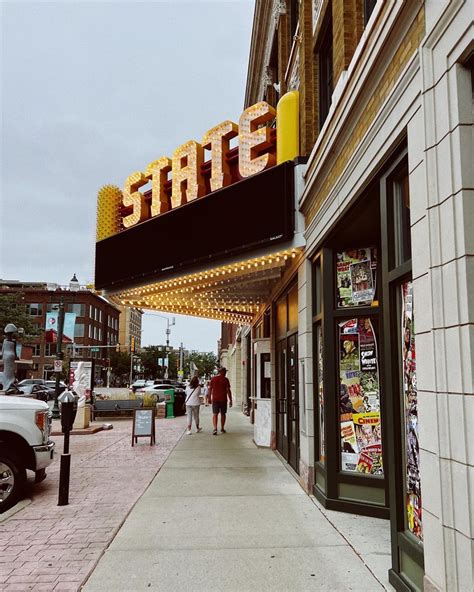 people walking down the sidewalk in front of a movie theater that is ...