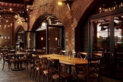 an indoor dining area with tables, chairs and lights hanging from the ...