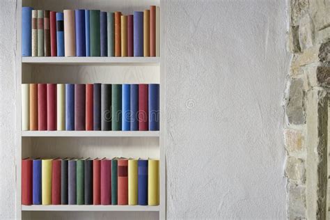 Beautiful Bookshelf with Colorful Books in a White Wall with Stones in ...