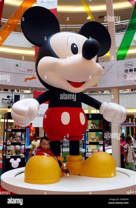 A boy sits below a giant Mickey Mouse statue on display during the ...