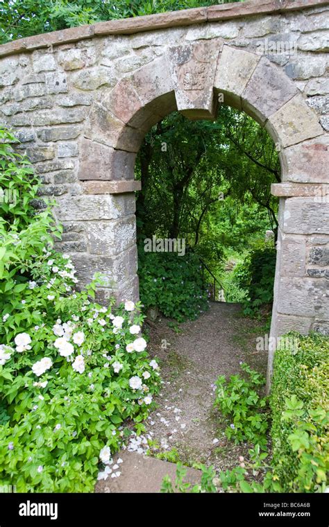 Stone archway in old garden wall with prominant keystone leading down ...