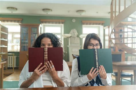 Women Covering Their Faces with Books · Free Stock Photo