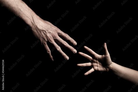 Hands reaching out to each other on dark black background Stock Photo ...