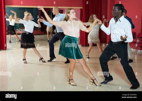 Adult dancing couples enjoying active boogie-woogie in modern studio ...