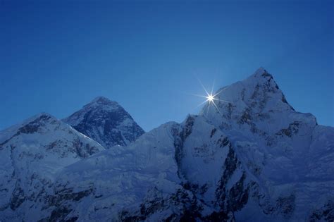 the sun shines brightly above some snow covered mountain peaks in the ...