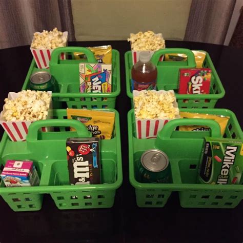 four green baskets filled with movie snacks and sodas on top of a black ...