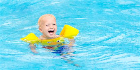 Toddler swimming in pool with swim floaties on; Courtesy of FamVeld ...