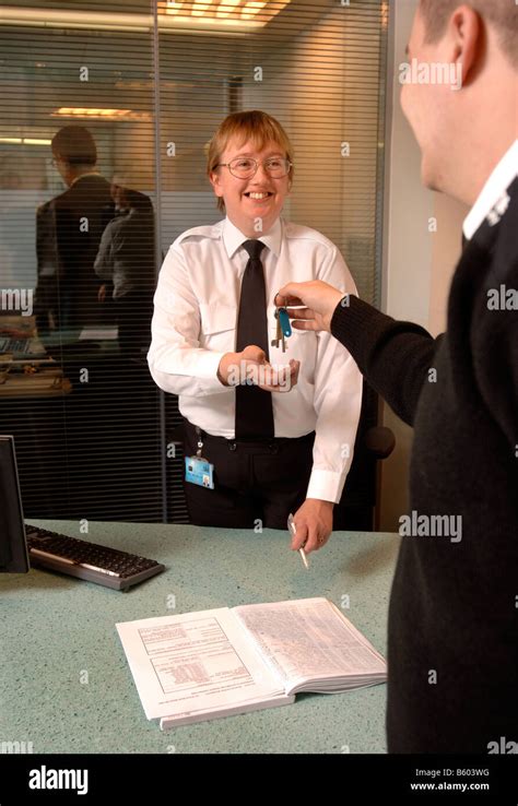 A SECURITY GUARD ON PATROL PASSES KEYS TO A FRONT DESK SECURITY OFFICER ...