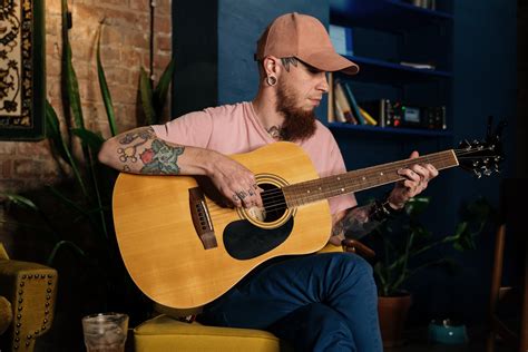 Man With Tattoos Playing an Acoustic Guitar · Free Stock Photo