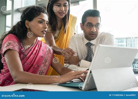 Three Indian Employees Working Together Around a Laptop Stock Photo ...