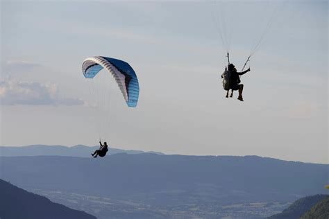 Unrecognizable people flying paragliders above mountains · Free Stock Photo