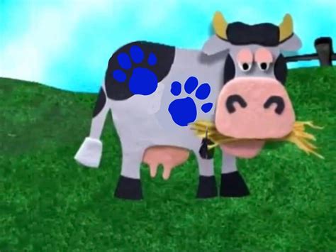 a cow that is standing in the grass with its paw print on it's face