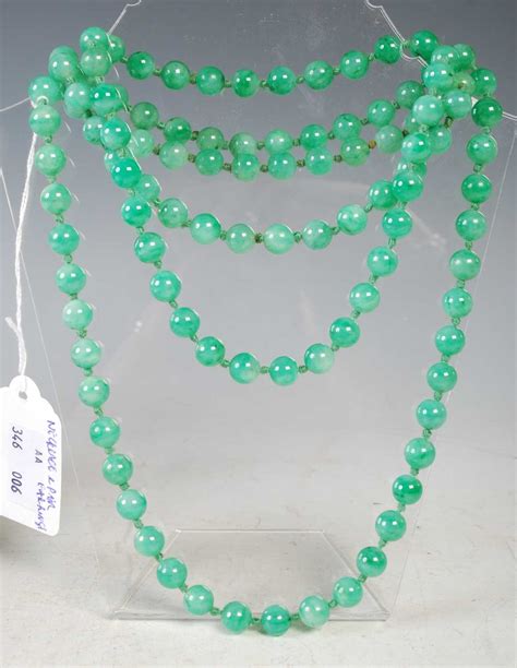 Lot 35 - A long green jade bead necklace, together