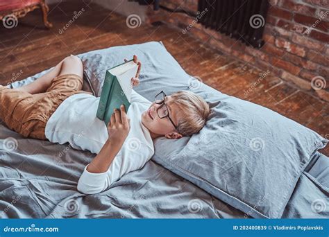 Cheerful Preschool Boy Reading a Book and Lying Down on a Bed Stock ...