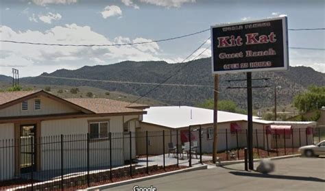 a motel sign in front of a fenced parking lot with mountains in the ...