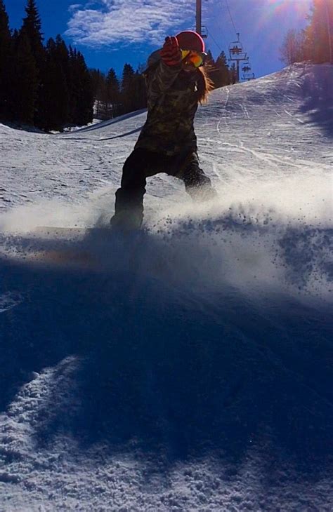 a person riding a snowboard down the side of a snow covered slope