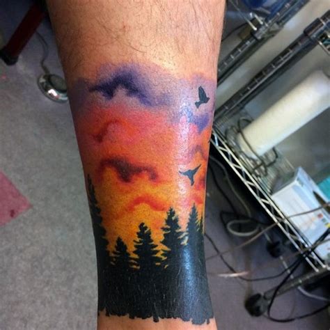 Little colorful sunrise above the forest tattoo on leg - Tattooimages.biz