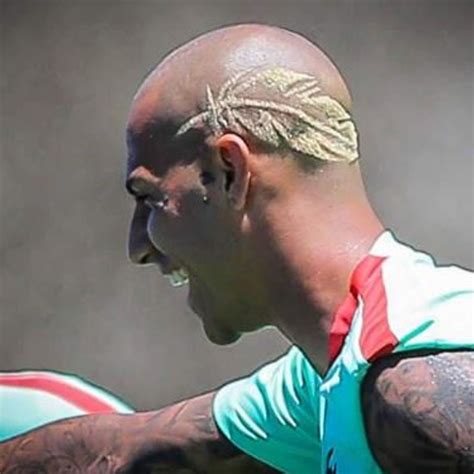 a bald man with tattoos on his head holding a rugby ball