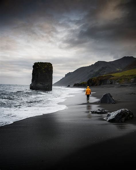 Man walking along black beach | Premium Photo - rawpixel