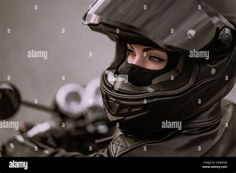 Stylish motorcyclist woman in helmet and leather jacket sitting on ...