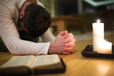 Young Man Praying, Kneeling, Bible and Candle Next To Him. Stock Photo ...