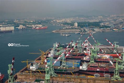 an aerial view of cargo ships docked in the water and cityscape behind them