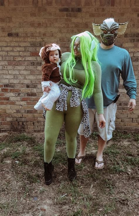 two people in costumes standing next to a brick wall and one is holding ...