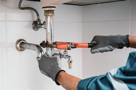 Premium Photo | Plumber using a wrench to repair water pipe under the sink.