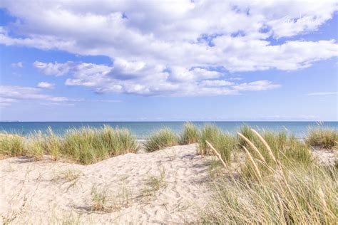 the beach is covered in sand and grass as well as some clouds over the ...