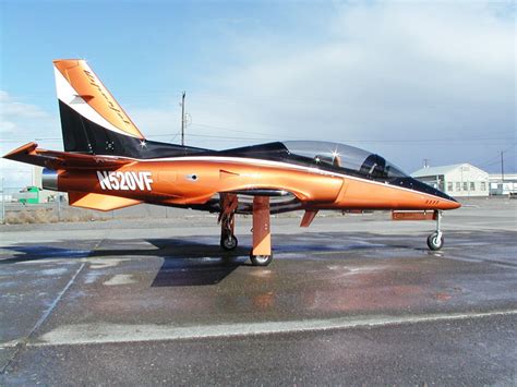 an orange and black jet sitting on top of an airport tarmac