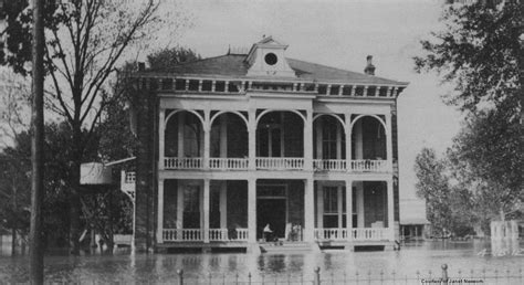 an old photo of a house in the middle of a flooded street