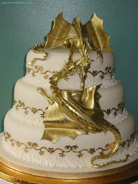 a white and gold wedding cake with a dragon on top