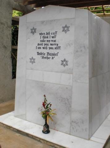 a white monument with writing on it and flowers in the foreground next ...