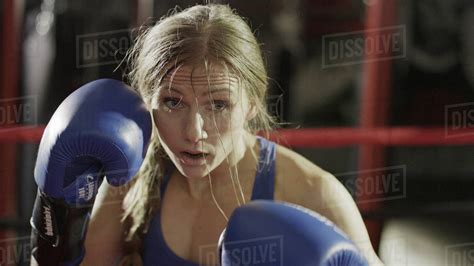 Close up of female boxer in boxing gloves standing in boxing ring ...