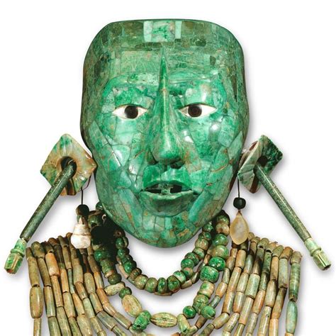 a green mask with long necklaces on it's face and two fingers in the ...