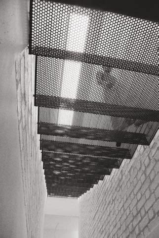 a man walking down a hallway next to a brick wall with a metal railing ...