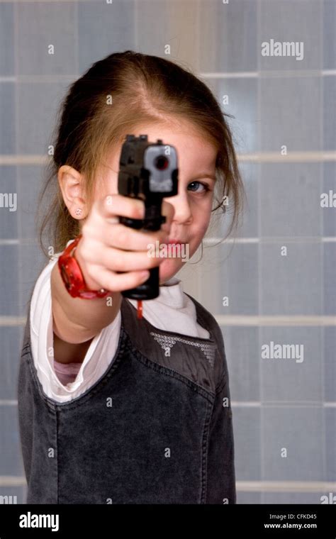 Concept of an aggressive young girl pointing gun towards the camera ...