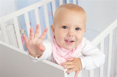 Portrait of a Cute Baby Waving Hello and Smiling from Crib Stock Photo ...