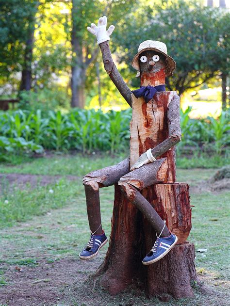 a statue of a man sitting on top of a tree stump in the grass with his ...