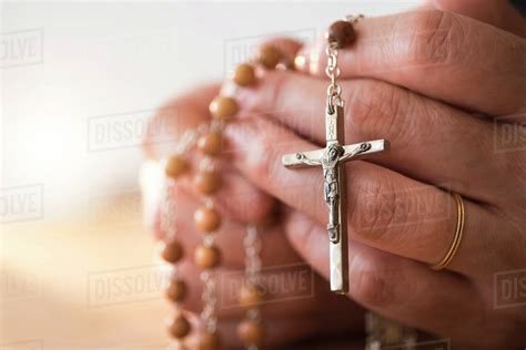 Woman praying with rosary beads in hands - Stock Photo - Dissolve