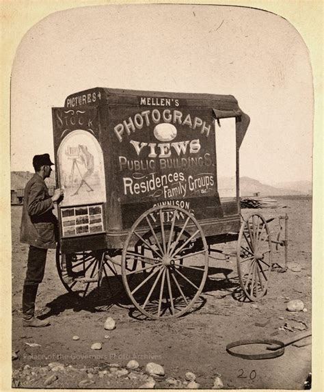 an old photo of a man standing next to a horse drawn cart in the desert