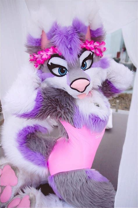 a purple and white stuffed animal holding a pink object in it's paws,