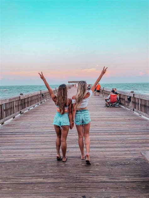 two girls standing on a pier with their arms in the air