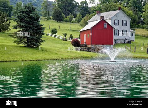 Farm house in summer landscape with large scenic pond and fountain with ...