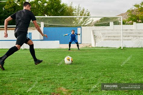 A soccer player takes a penalty kick against a goalkeeper — stadium ...