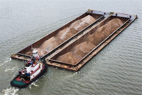 Tugboat pushing barges of sand, high angle view - Stock Photo - Dissolve