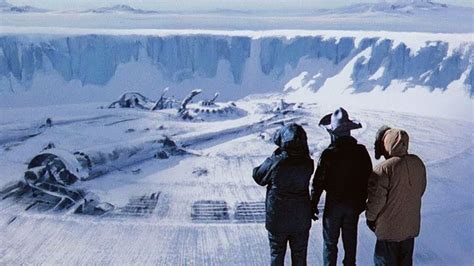 three people standing on top of a snow covered mountain looking out at ...