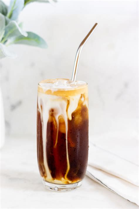 an iced americano in a glass with ice and caramel drizzle on top